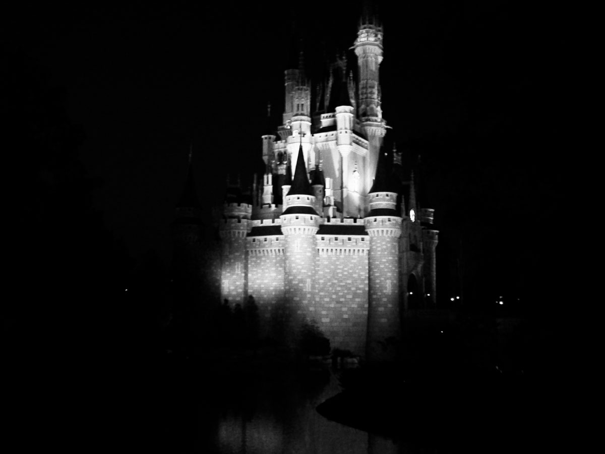 A floodlit castle at night, the only block of light in a black frame.