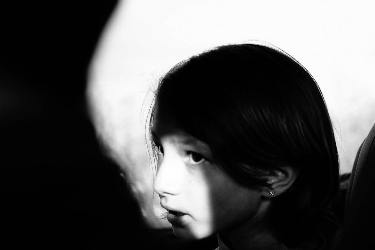 A child's face in a band of light, a dark shape in the foreground.
